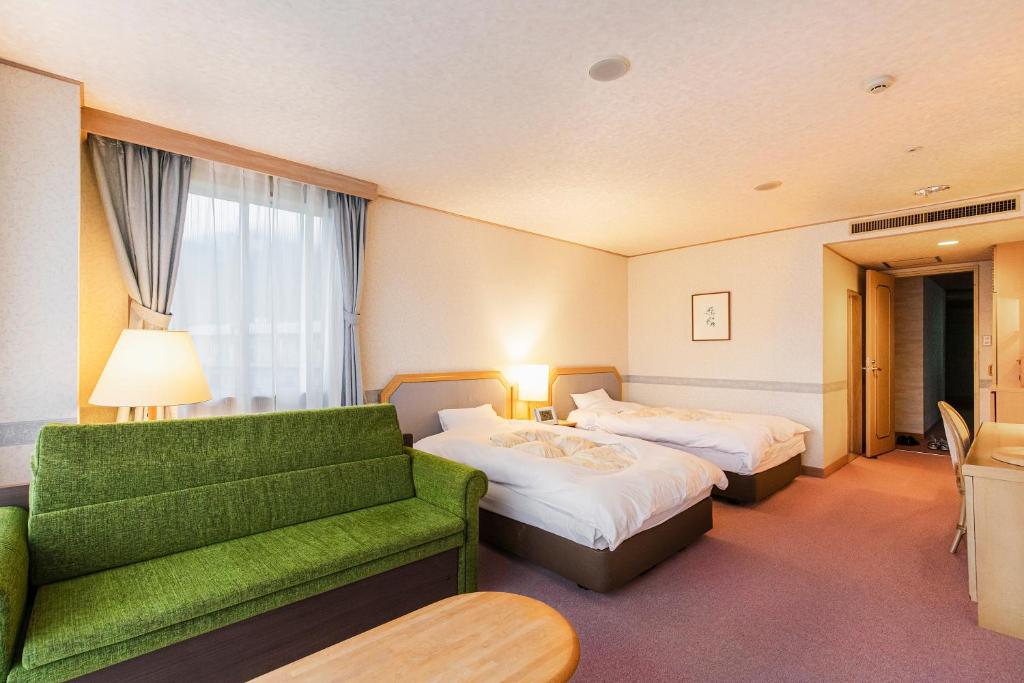 une chambre d'hôtel avec deux lits et un canapé vert dans l'établissement Yufuin Kotobuki Hananosho, à Yufu
