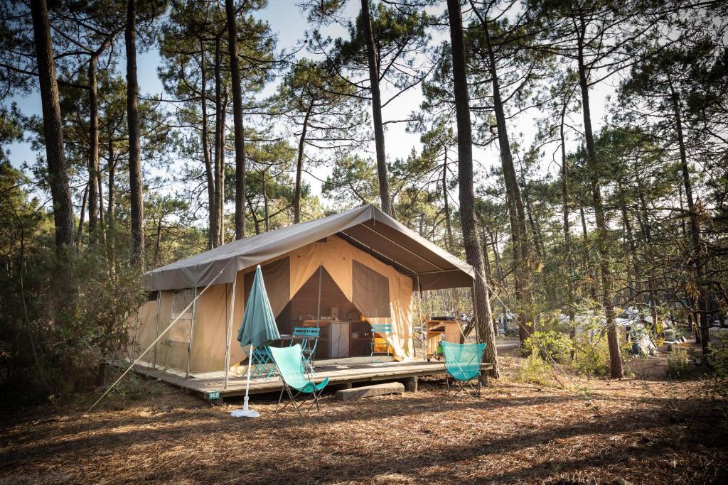 une tente et deux chaises dans les bois dans l'établissement Huttopia Lac de Carcans, à Carcans