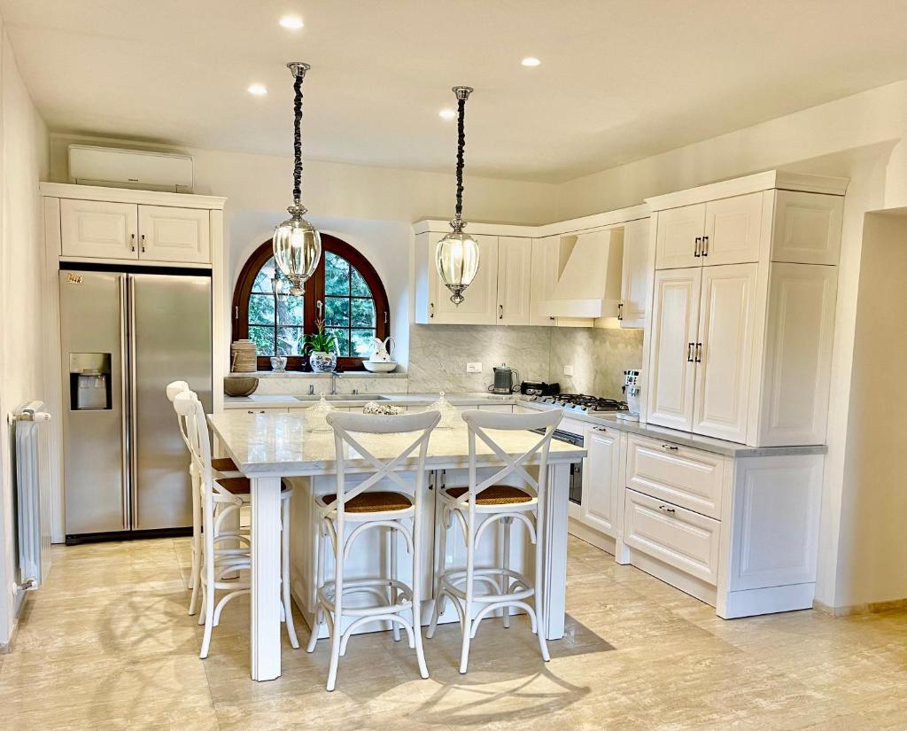 une cuisine avec des armoires blanches et une table avec des tabourets dans l'établissement Villa Podere Del Grasso, à Castel del Piano