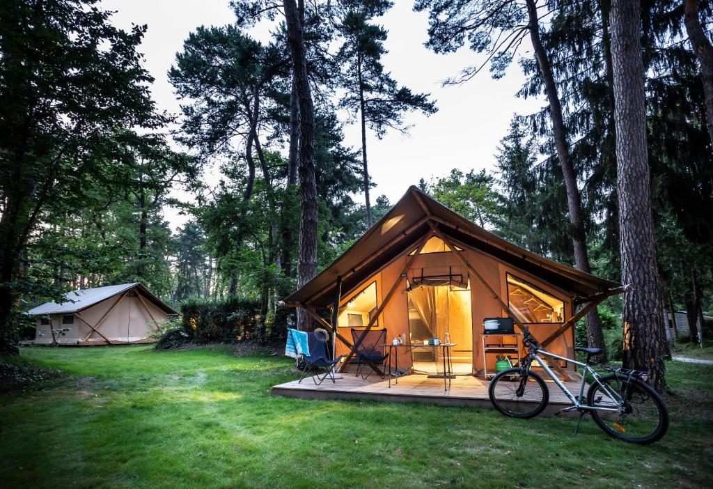 une tente avec un vélo garé devant elle dans l'établissement Camping La Pinède, à Excenevex