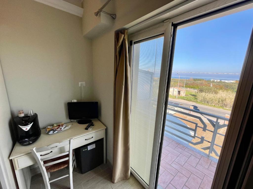 Cette chambre dispose d'un bureau avec un ordinateur et d'une porte coulissante en verre. dans l'établissement Hotel Al Rustico, à Crosia