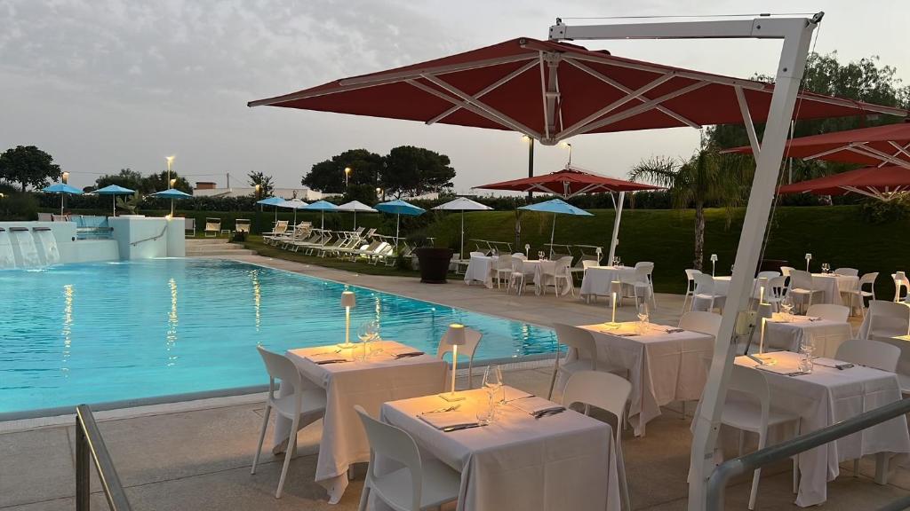 un restaurant avec des tables et des parasols à côté d'une piscine dans l'établissement Seawater Hotel Bio & Beauty Spa, à Marsala