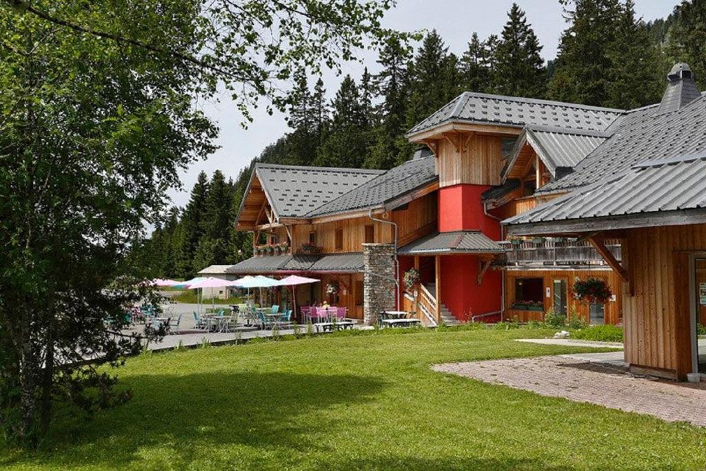 un grand bâtiment en bois avec une pelouse devant lui dans l'établissement Les Roches 1500, à Mieussy