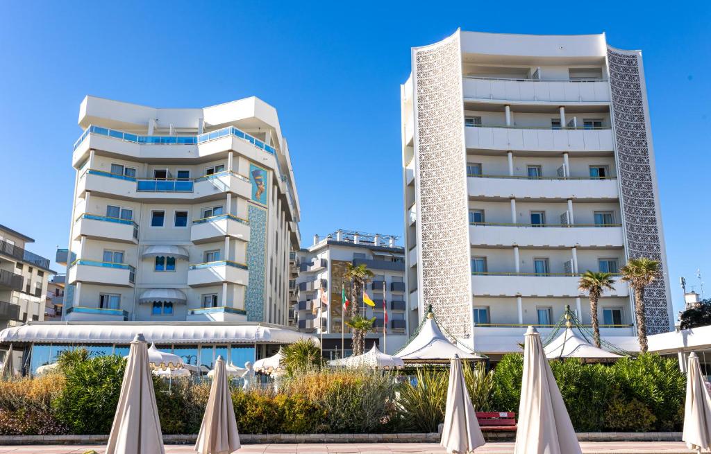 une rangée de parapluies blancs devant un bâtiment dans l'établissement Luxor e Cairo The Beach Resort, à Lido di Jesolo