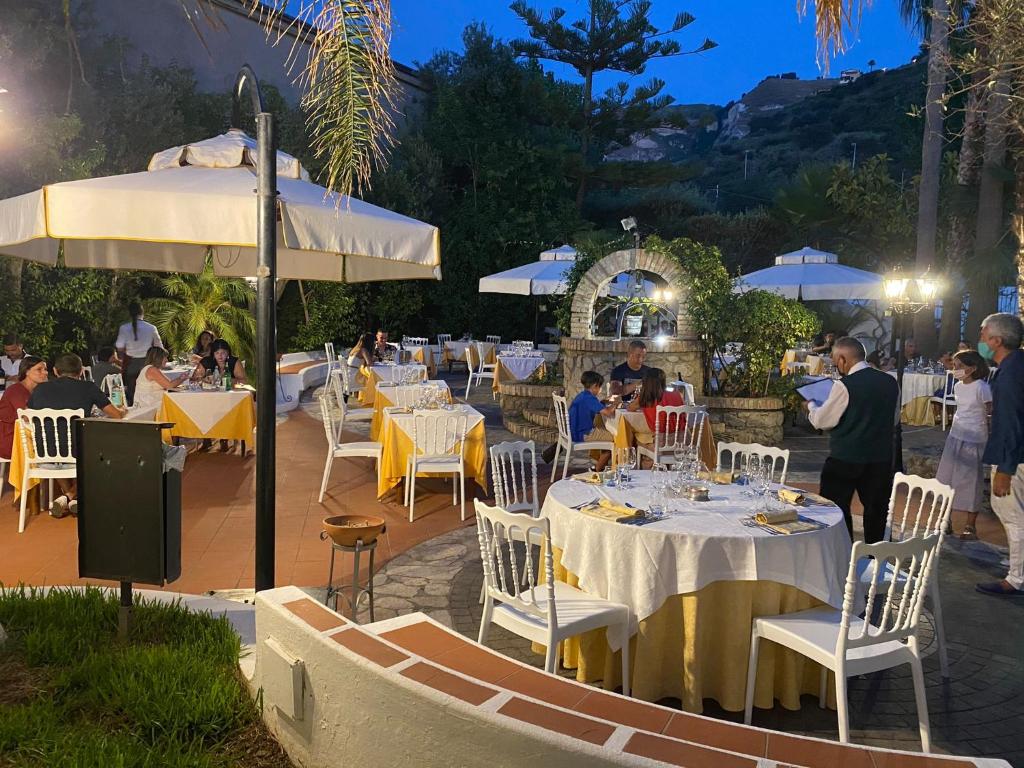un restaurant avec des tables blanches, des chaises et des parasols dans l'établissement Hotel Tirreno, à Parghelia 73 autres photos