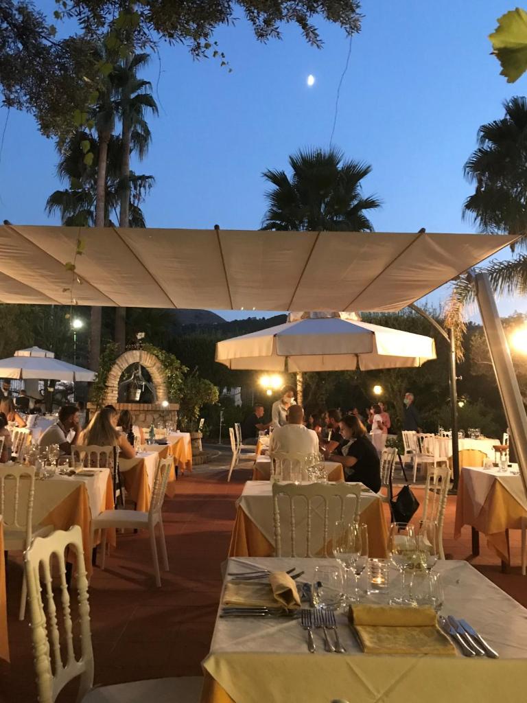 un groupe de personnes assises à des tables dans un restaurant dans l'établissement Hotel Tirreno, à Parghelia