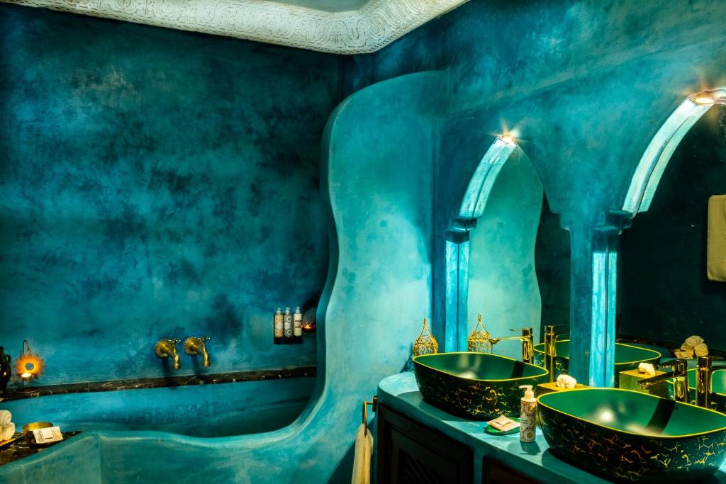 une salle de bain bleue avec un lavabo et un miroir dans l'établissement Maïpa Boutique Riad, à Marrakech 37 autres photos