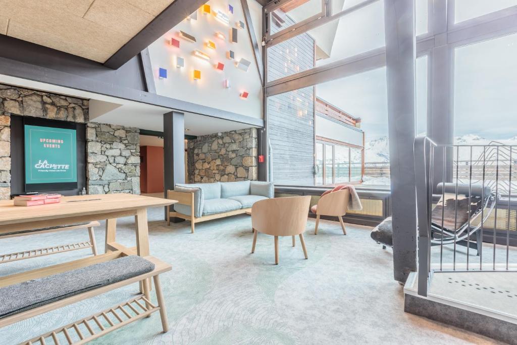 - un salon avec une table, des chaises et une télévision dans l'établissement La Cachette, Friendly Hotel & Spa, à Arc 1600