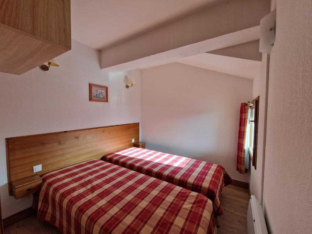 - une petite chambre avec un lit et une couverture rayée dans l'établissement Appartement au Chalet d'Orcières Merlette, à Orcières