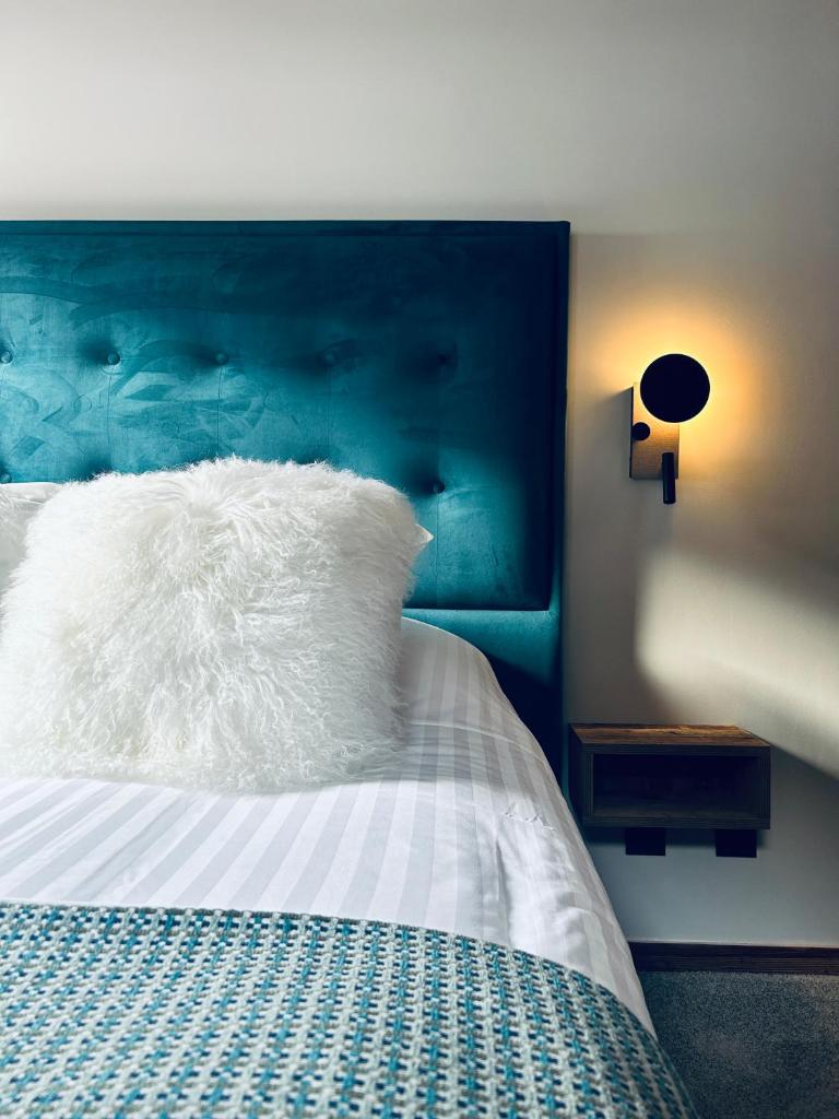 - un lit avec un oreiller blanc et une tête de lit bleue dans l'établissement Hameau des Prodains - Résidence, à Morzine