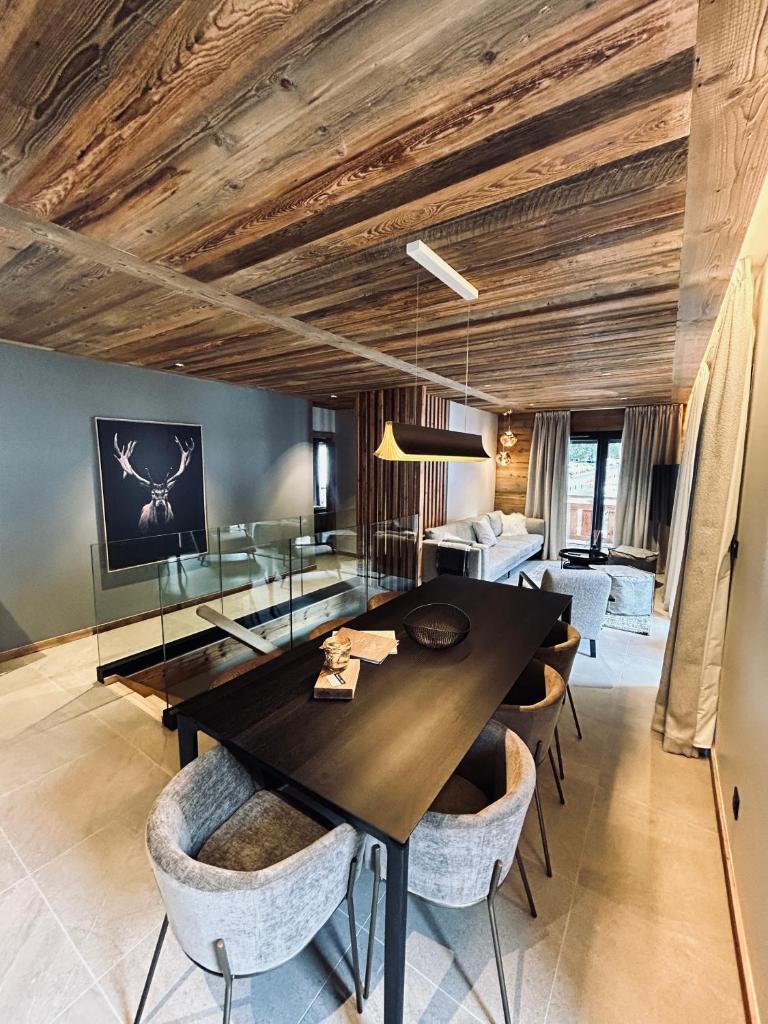 une salle à manger avec une table et des chaises noires dans l'établissement Hameau des Prodains - Résidence, à Morzine