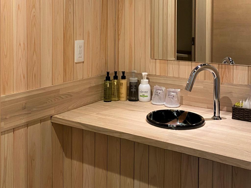 un comptoir de salle de bain avec un lavabo et un miroir dans l'établissement Kashoutei Hanaya, à Noboribetsu