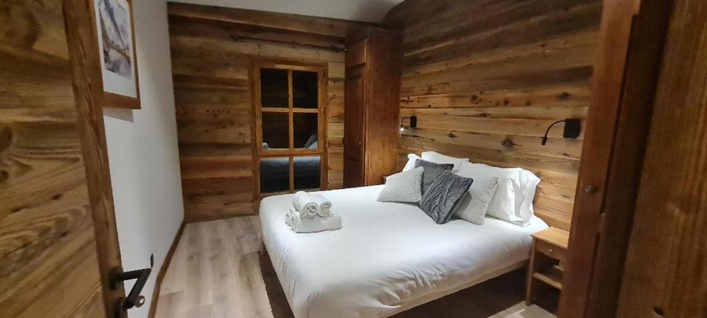 une chambre avec un lit avec des draps blancs et des oreillers dans l'établissement Refuge du Montagnard ARCS 1950, à Arc 1950