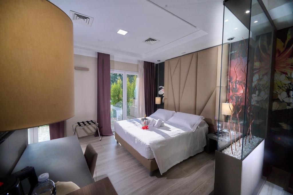 - une chambre avec un lit blanc et un mur en verre dans l'établissement PARK HOTEL LE DUNE DI GIOVINO, à Catanzaro Lido