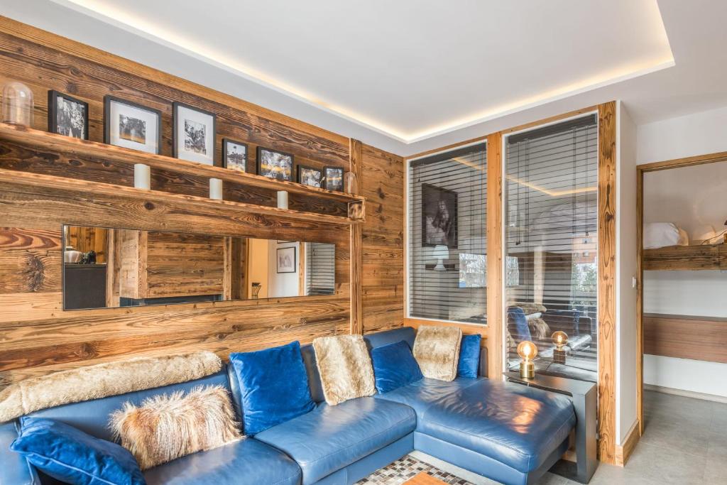 - un salon avec un canapé bleu et des murs en bois dans l'établissement Appartement Perchets - Welkeys, à Megève