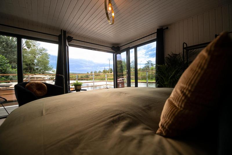une chambre avec un grand lit avec une grande fenêtre dans l'établissement Gîte Seine & Nature Le Bâbord, à Bennecourt