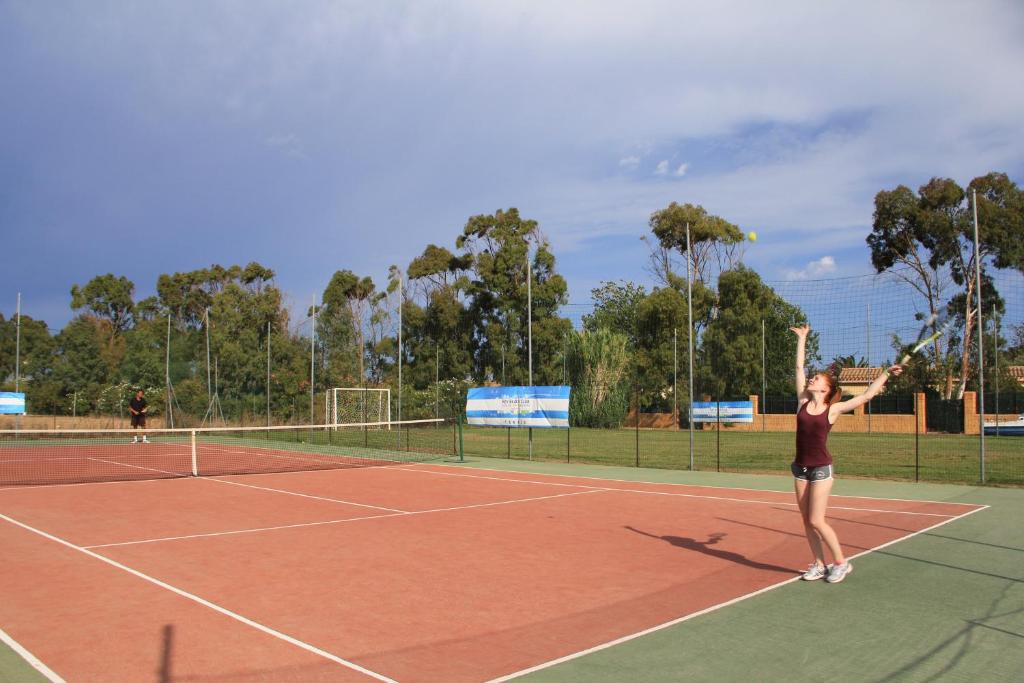 une femme servant une balle de tennis sur un court de tennis dans l'établissement Rey beach Club, à Monte Nai