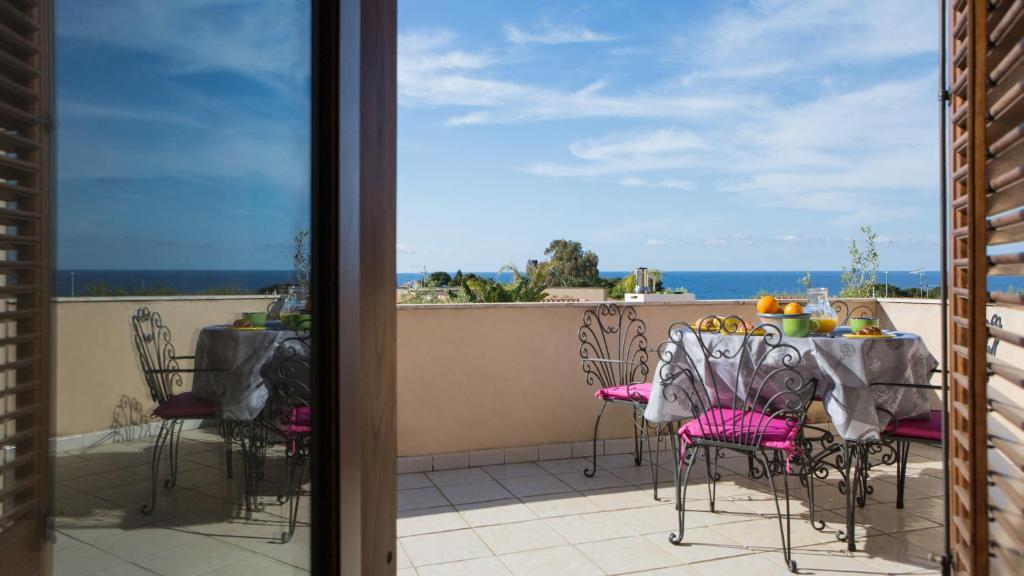 une table et des chaises sur un balcon avec vue sur l'océan dans l'établissement Villa Mazzaforno a Cefalu' by Wonderful Italy, à Cefalù