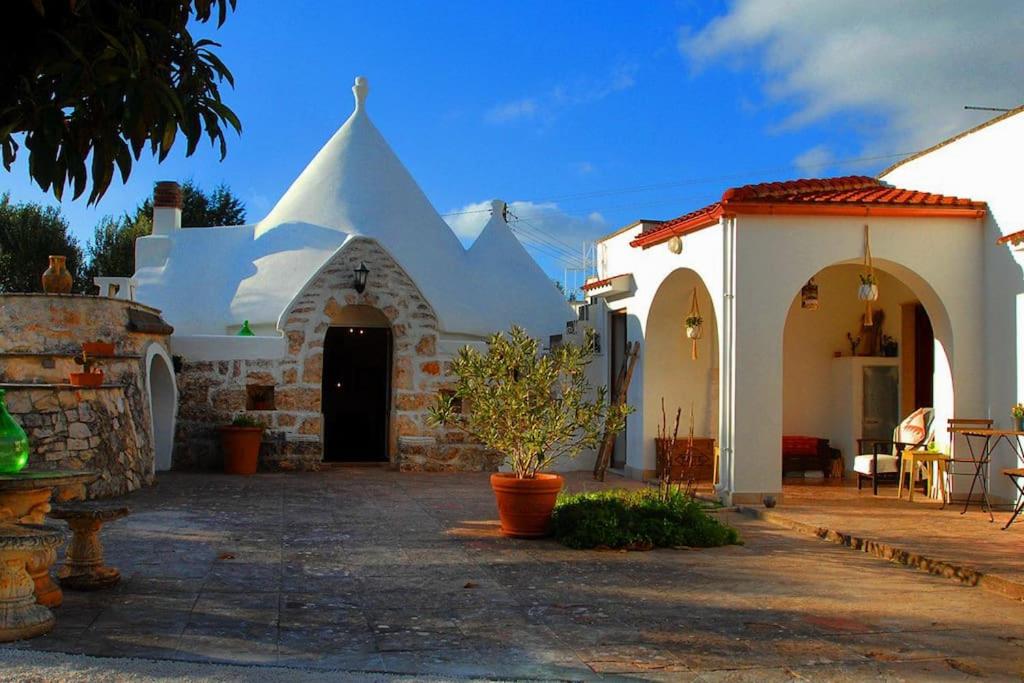 un bâtiment blanc avec un toit pointu dans l'établissement Beautiful Trulli in the heart of the Valle d Itria, à Ostuni