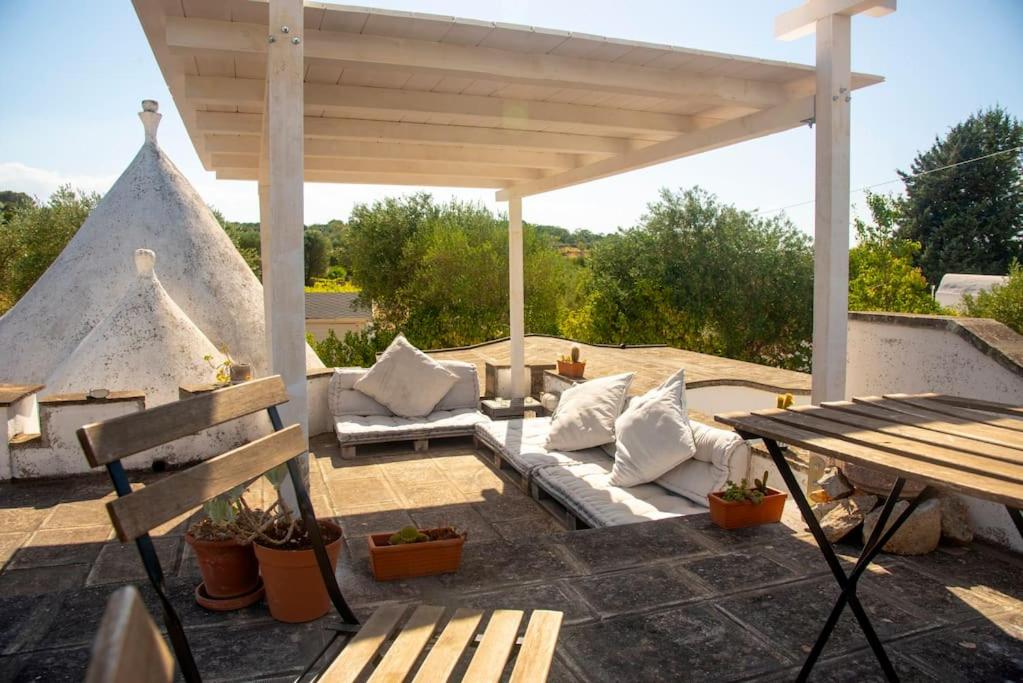 une pergola avec un canapé et une table dans l'établissement Beautiful Trulli in the heart of the Valle d Itria, à Ostuni