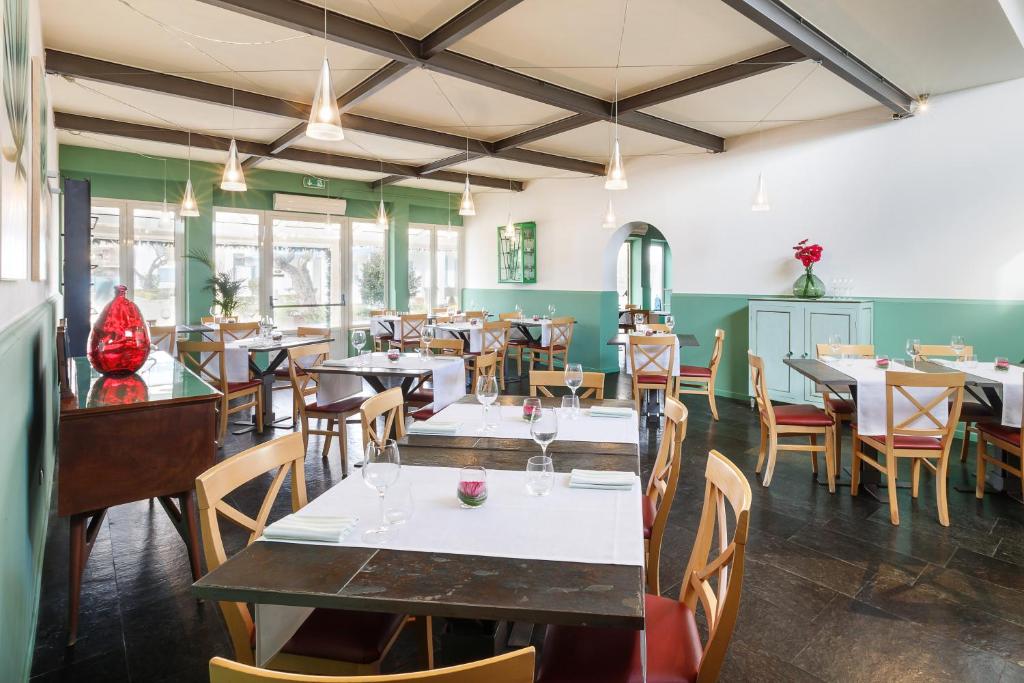 une salle à manger avec tables, chaises et fenêtres dans l'établissement Riva di Palo Beach Hotel, à Ladispoli