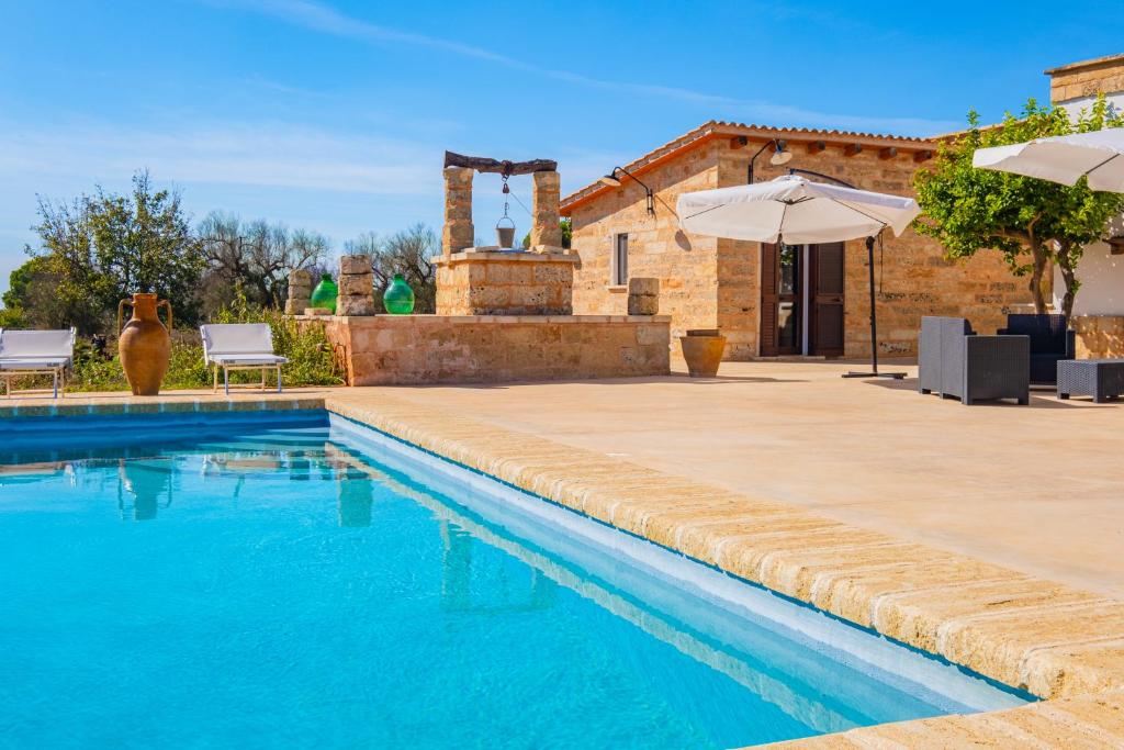 - une piscine avec un parasol en face d'une maison dans l'établissement Villa Nonno Toto by HDSalento, à Acquarica del Capo