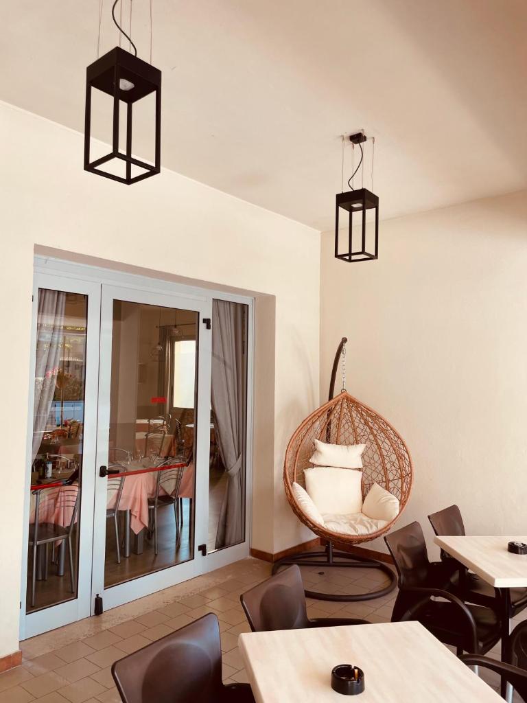 une chambre avec des tables, des chaises et une chaise en osier dans l'établissement Hotel Vera, à Cesenatico