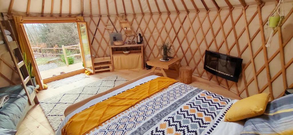 une chambre avec un lit et une télévision dans une pièce dans l'établissement Yourte des Verts Bois, à Fréland