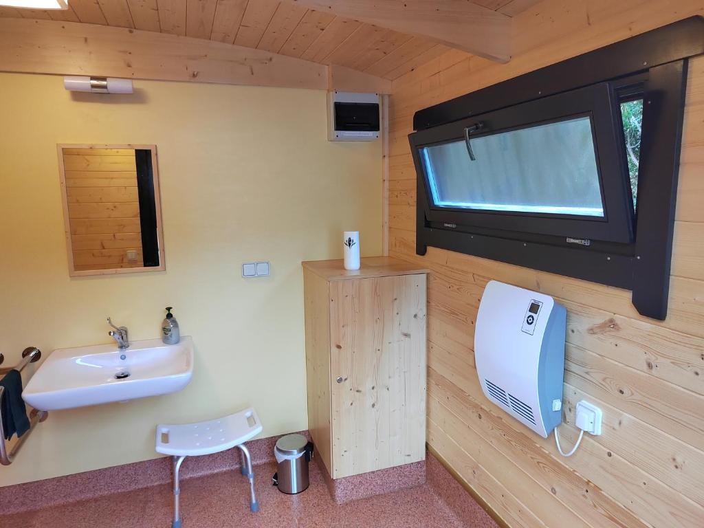 une salle de bain avec un lavabo et une télévision au mur dans l'établissement Yourte des Verts Bois, à Fréland