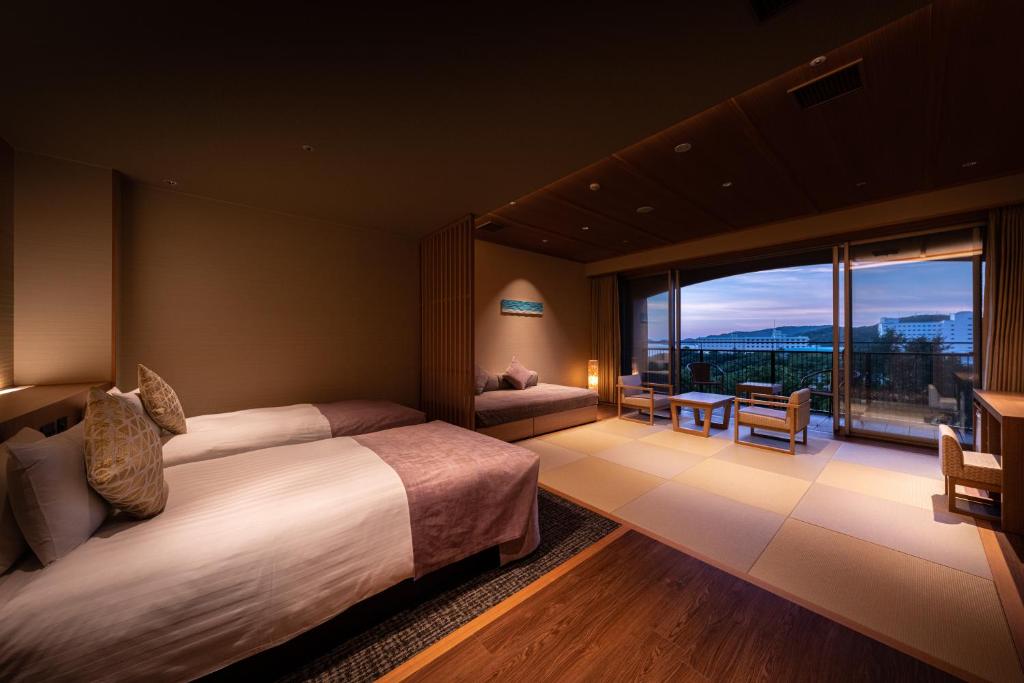 une chambre d'hôtel avec deux lits et une grande fenêtre dans l'établissement KAMENOI HOTEL Toba, à Toba