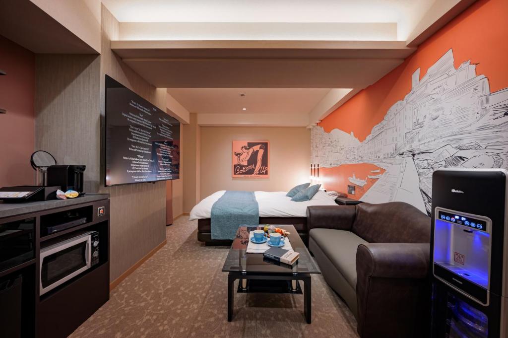 une chambre d'hôtel avec un lit, un canapé et une télévision dans l'établissement Hotel WILL BASE 鶴見, à Yokohama