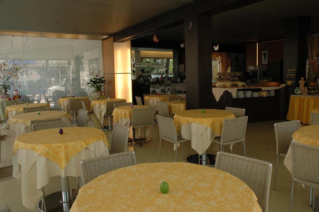 une salle à manger avec des tables, des chaises et un tissu de table jaune dans l'établissement Hotel Elvia, à Lignano Sabbiadoro