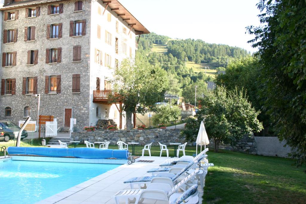 un hôtel avec une piscine entourée de chaises et un bâtiment dans l'établissement Grand Hotel de Valloire et du Galibier, à Valloire