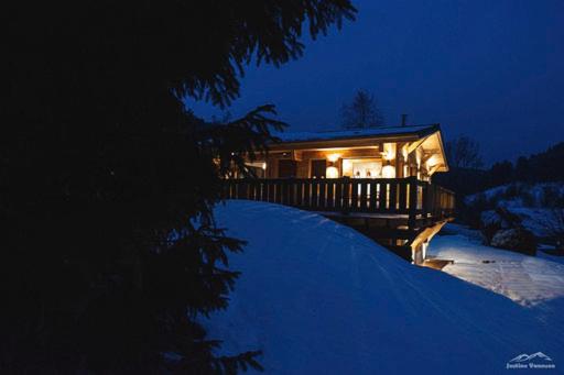 une maison avec une terrasse couverte dans la neige la nuit dans l'établissement L'instant chalet Lodge 17, à Gérardmer