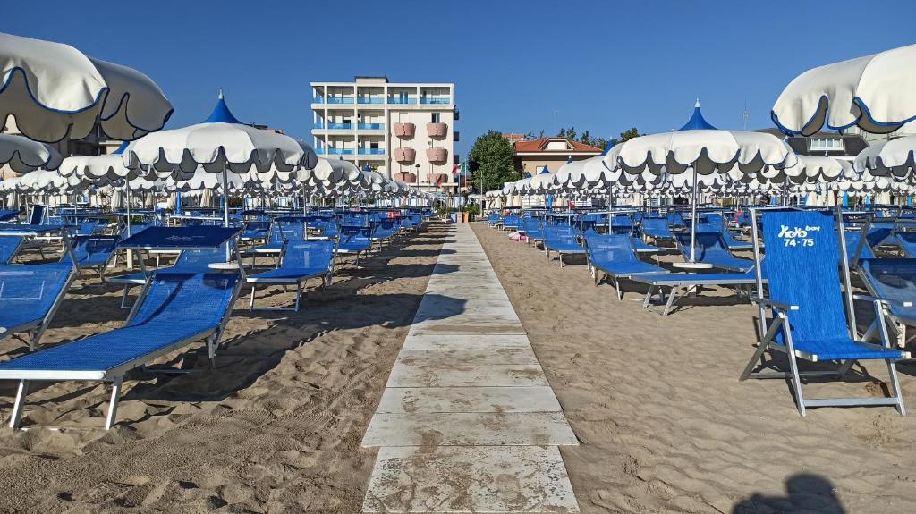- une rangée de chaises et de parasols bleus sur une plage dans l'établissement Hotel La Caravella, à Bellaria-Igea Marina