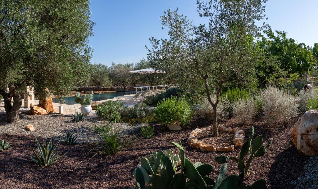 un jardin avec une piscine, des arbres et des plantes dans l'établissement Casa Amahoro, à Ostuni