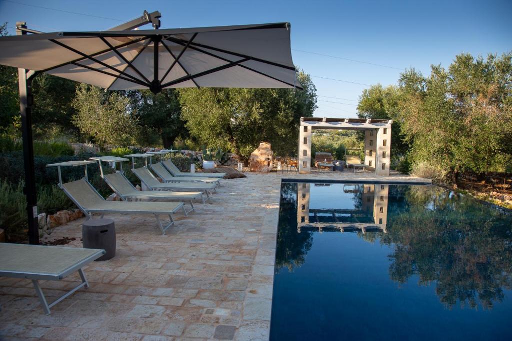 - une piscine avec des chaises longues et un parasol à côté dans l'établissement Casa Amahoro, à Ostuni