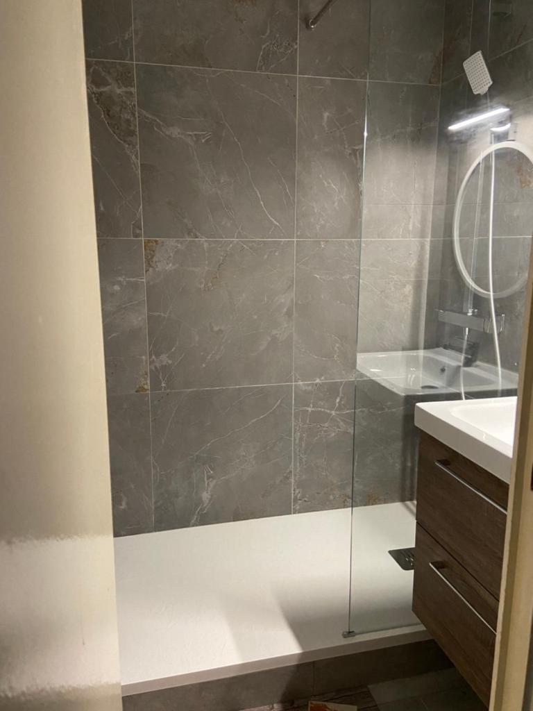 une salle de bain avec une douche avec un lavabo et un miroir dans l'établissement Appartements au cœur de la station de ski "La Foux D'allos", à Allos