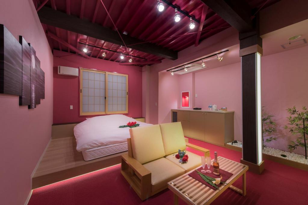 - une chambre aux murs roses avec un lit et une table dans l'établissement ホテル 鳳凰 大人専用, à Hachioji