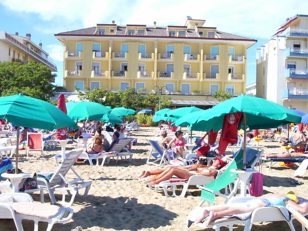 un groupe de personnes assises sur une plage avec des parasols dans l'établissement Hotel Continental, à Lido di Jesolo