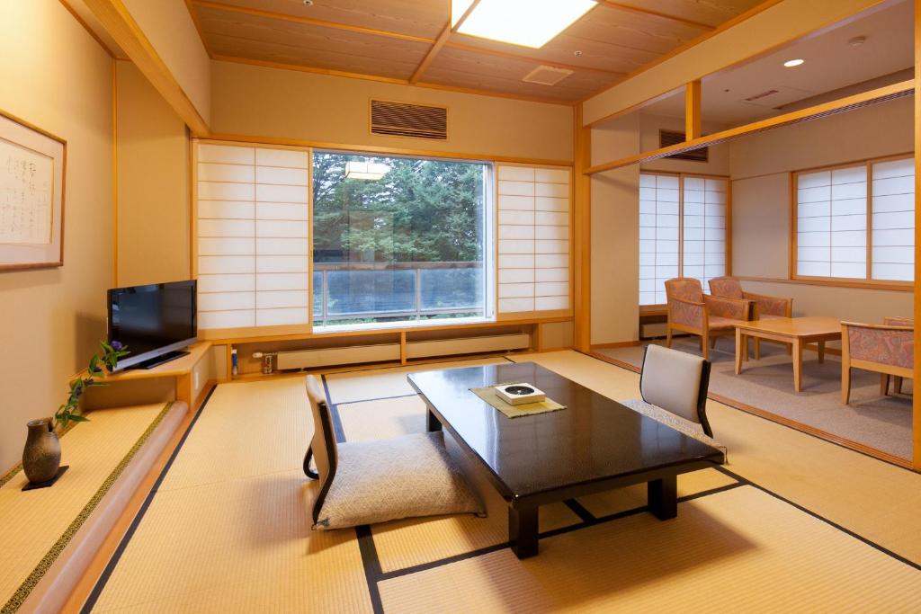 une pièce avec une table, des chaises et une télévision dans l'établissement Zazan minakami, à Minakami