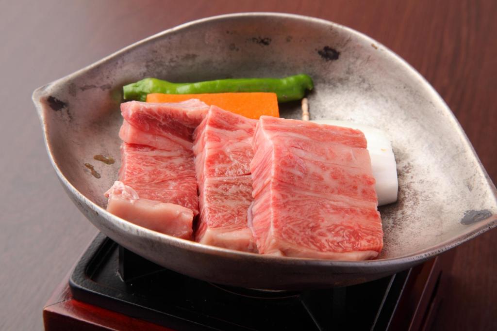 un poêle rempli de viande et de légumes dans l'établissement Shikanoyu Hotel, à Komono