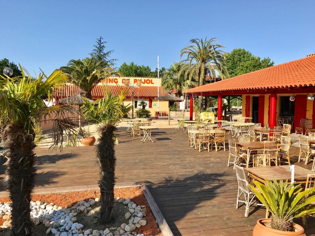 un patio avec des tables et des chaises devant un restaurant dans l'établissement De Pujol Greenchalets Argeles sur Mer, à Argelès-sur-Mer