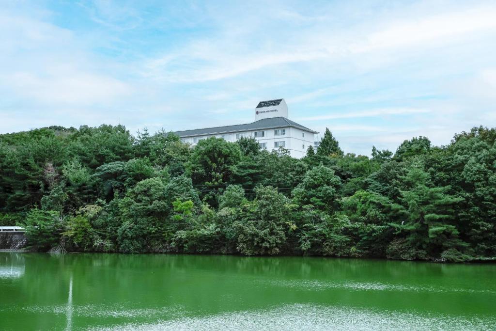un bâtiment situé au sommet d'une colline à côté d'un lac dans l'établissement KAMENOI HOTEL Kanonji, à Kanonji