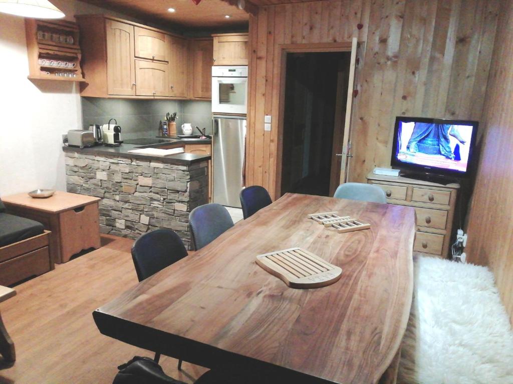 Il comprend une cuisine avec une table en bois, des chaises et une télévision. dans l'établissement Appartement au lac ski aux pieds, à Tignes 8 autres photos