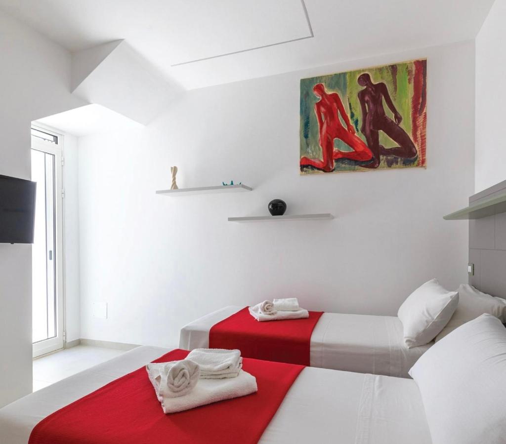 Cette chambre blanche comprend 2 lits et une couverture rouge. dans l'établissement Villa Skyline- Otranto, à Otrante