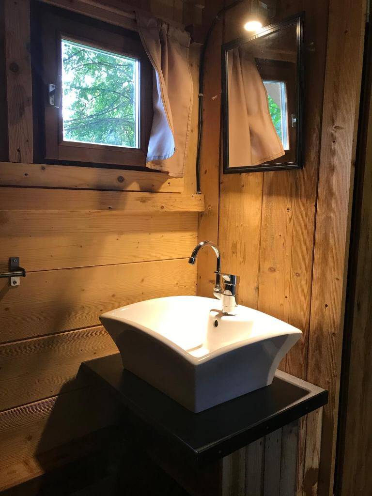 La salle de bains en bois est pourvue d'un lavabo blanc et de 2 fenêtres. dans l'établissement Camping Du Perche Bellemois, à Bellême