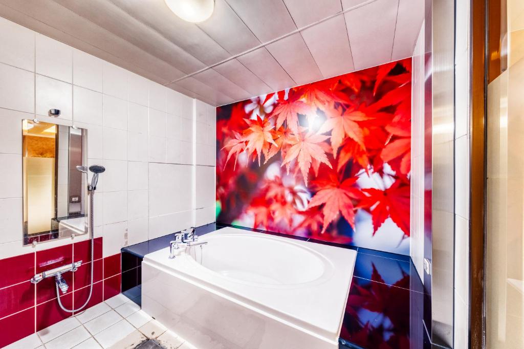 La salle de bains est pourvue d'une baignoire et d'un mur rouge. dans l'établissement Hotel Lotus Higashiosaka -Adult Only, à Osaka