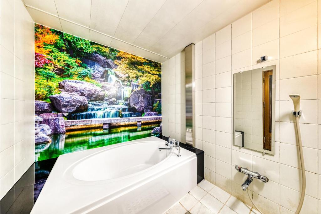 une salle de bain avec une baignoire et un tableau au mur dans l'établissement Hotel Lotus Higashiosaka -Adult Only, à Osaka