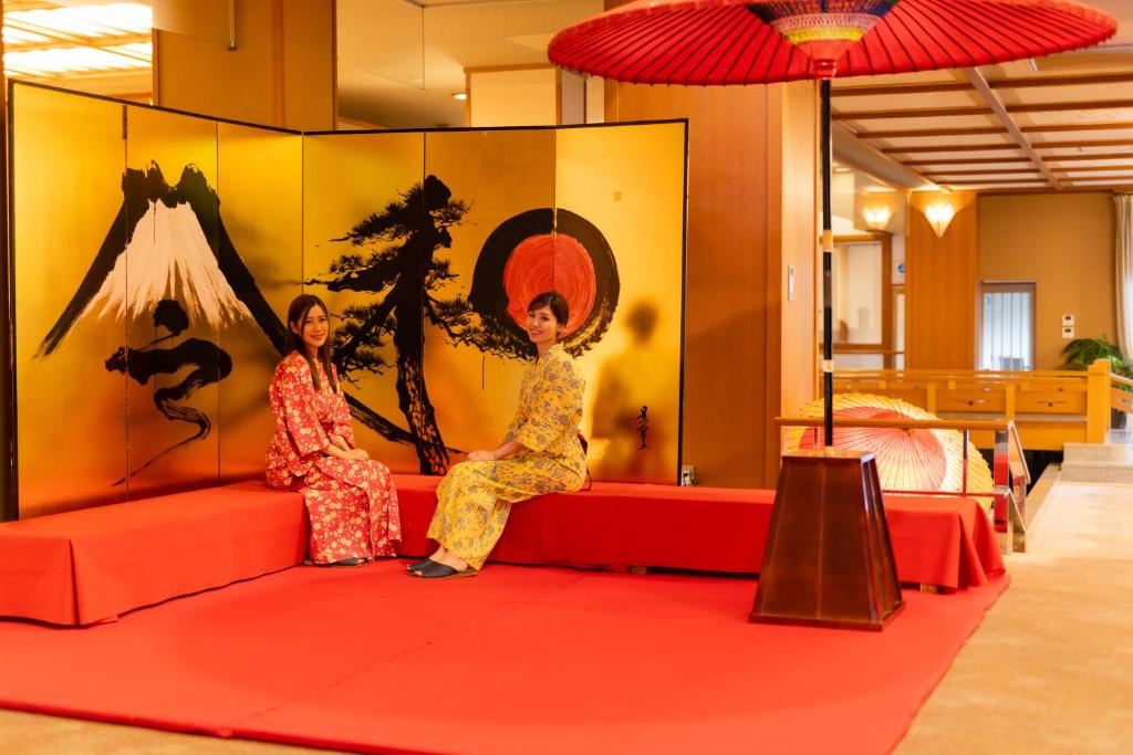 2 femmes assises sur un canapé rouge dans une pièce dans l'établissement Hotel Hoho "A hotel overlooking the Echigo Plain and the Yahiko mountain range" formerly Hotel Oohashi Yakata-no-Yu, à Niigata